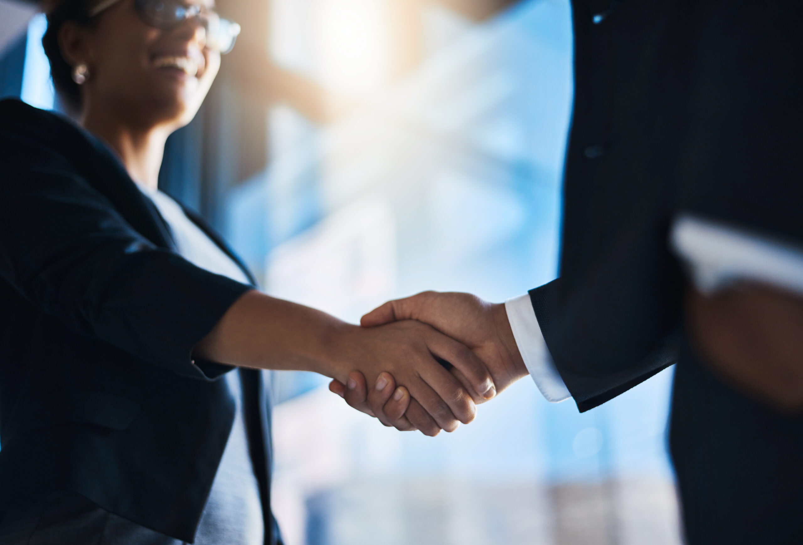Two business professionals shaking hands in a modern corporate environment