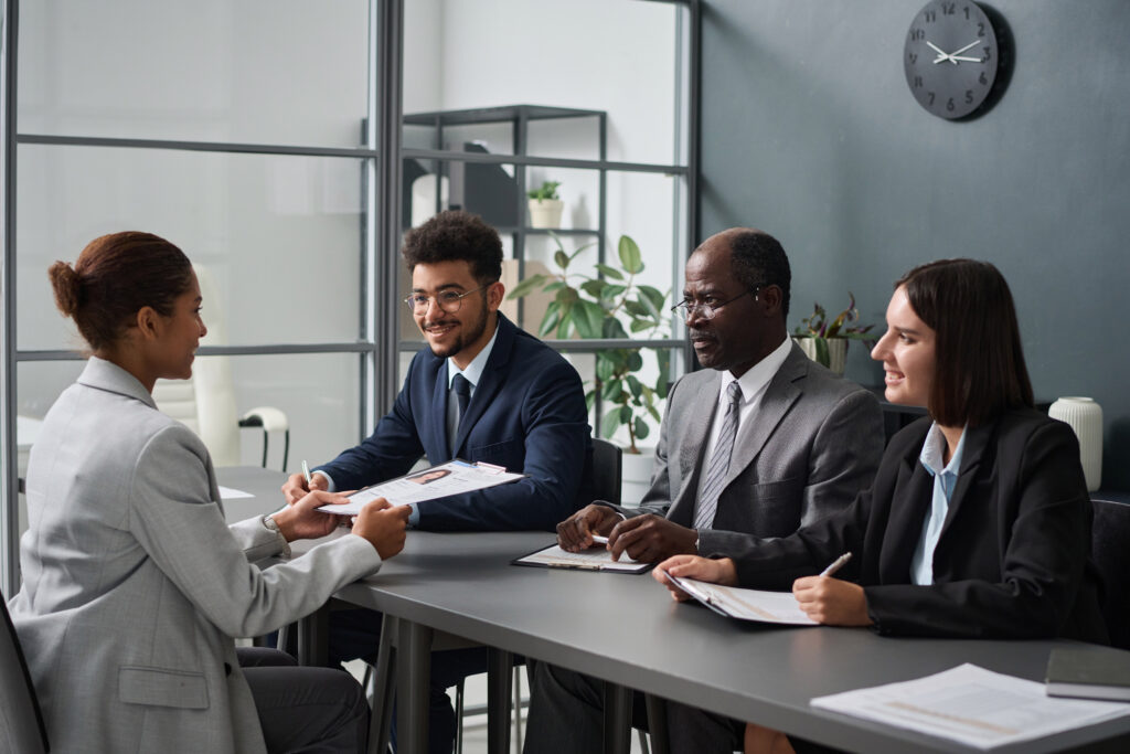 A young professional being interviewed by three recruiters in a modern office setting